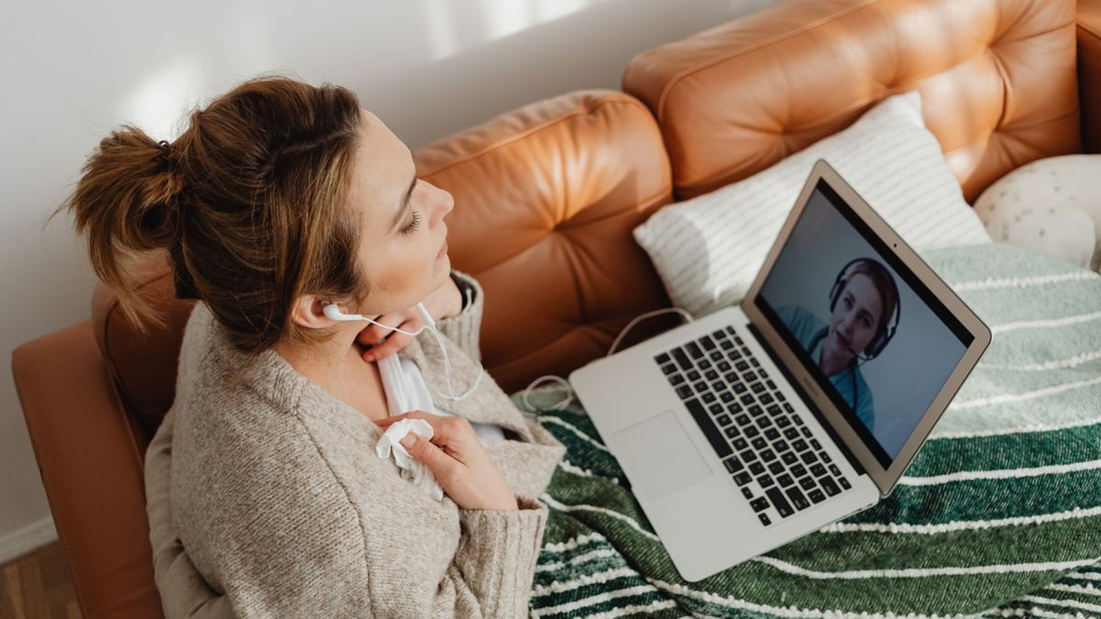 A woman on a video call from a cozy couch at home